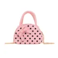 Close-up view of a pink polka-dot bag with a bow, top handle, and gold-tone chain strap. - Pink
