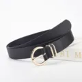 Ceinture noire en similicuir avec boucle dorée à double anneau, présentée pliée sur fond blanc - 106*2.8 / Noir