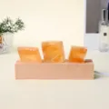 Tres cristales ámbar translúcidos sobre una base de madera clara, lámpara nocturna USB decorativa - Calcita