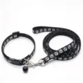 Black nylon dog collar and leash set with silver paw prints, a bell and metal clip, laid out on white - Black Paw Print Set