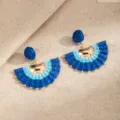 Pair of blue fan-shaped woven earrings with gold bead accents, displayed on beige linen fabric. - Blue (E1957-2)