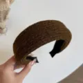 Close-up van een bruine, pluizige haarband met breistructuur en zwarte stoffen voering - Bruin