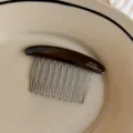 Close-up of a dark brown resin comb with silver metal teeth and "FRANCE Handmade" lettering - Black Gold Label Oval Comb