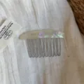 Close-up of an iridescent pearlescent curved comb back with slim metal teeth on linen fabric - Mermaid Multicolor Comb