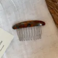 Flat lay of a curved tortoiseshell hair comb with fine metal teeth on natural linen - Tortoiseshell Gold Label Comb