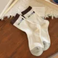 Thick knitted crew socks in cream with dark brown cuffs, gray heels and colorful MORE lettering - One Size / Cream White