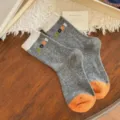 Gray knitted mid-calf socks with cream cuffs, orange heels and toes, and colorful MORE lettering - One Size / Dark Gray