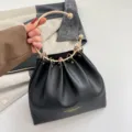 Detalle de un bolso negro fruncido de polipiel lisa con un asa de aro metálico dorado - Negro