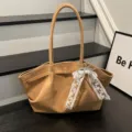 Detail view of a tan suede-look bag with gold clasp, white lace bow and pearl charm - With Scarf / Khaki