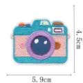 Detail van een kleurrijke geborduurde camerapatch met turquoise, roze en paarse steken, 5,9 × 4,5 cm - Groene Camera (9344-4)