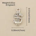 Close-up of a silver dollar-sign charm with clear stones and a top loop on beige fabric - Silver