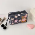 Schwarzer Karostoff mit Bärenmotiven, Reißverschluss und zwei Pompon-Anhängern vor hellem Grund - Schwarz