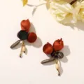 Close-up of rust-red fabric flower earrings with dark beads, cream drops and fine gold chains - Style 10 (202610)