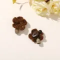 Two brown crocheted flower ornaments, one with a wooden leaf detail, arranged on a pale surface - Style 2 (202610) / 1 Piece (3.2cm)