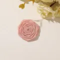 Close-up of a pink satin ribbon rose with layered petals on a pale surface beside flowers - Style 35(A09-2-1) / 1 Piece Pack