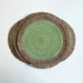 Round woven placemats with natural fringe and green spiral centers, stacked on a white background - Seaweed Green (Jute Tassel)