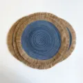 Round woven placemat with a blue spiral center and natural jute fringe, shown stacked - Blue (Jute Tassel)