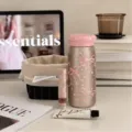 Scena su un tavolo con tazza termica color champagne, coperchio rosa e motivi di fiocchi e cuori - 220ml / Perla di Raso (Semplice)