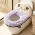 Close-up of a lavender plush toilet seat cover with a smiling sheep motif, shown on a white toilet - Sheep / Purple