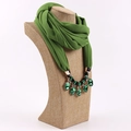 Dettaglio di sciarpa in chiffon verde scuro con collana di pietre su manichino beige - Verde Primavera