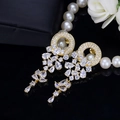 Detailed close-up of golden teardrop earrings with white AAA zircons on black background - Gold Plated White Zircon