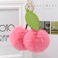 Detailed shot of pink faux fur cherry keychain with green leather leaf and gold metal ring - Deep Pink
