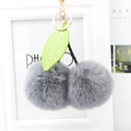 Detailed view of gray faux fur cherry keychain with green leaf and gold metal ring - Medium Grey