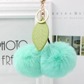Detail of mint green fluffy cherry fur pom pom keychain with green leather leaf and gold clasp - Mint Green