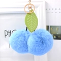 Close-up of fluffy light blue faux fur cherry keychain with green leaf and golden clasp - Blue
