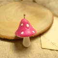 Macro detail of a small resin mushroom pendant with pink cap and white dots on a rustic base - Rose Red