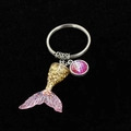 Close-up of a gradient pink mermaid tail keychain with glitter and fish scale charms - Rose & Gold