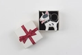 Detail view of a white bull terrier keychain in a black gift box with a red silk ribbon - White Dog with Gift Box