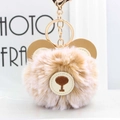 Macro shot of a fluffy brown bear plush keychain with a gold metal clasp and leather logo - Khaki Frost