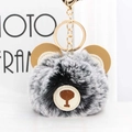 Close-up of a fluffy plush bear keychain with grey faux fur and a golden metal ring - Black Frost