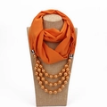 Details eines orangefarbenen Schals mit goldener Perlenkette auf einer Schaufensterpuppe - Orange