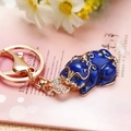 Blue enamel Pixiu keychain with crystals and gold-plated finish on pink floral background - Royal Blue Fortune Pixiu
