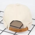 Dettaglio del cinturino in pelle marrone e incisione 1986 sul berretto docker beige - Regolabile / Beige