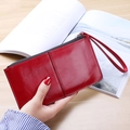 Long red leather zip wallet for women featuring a wrist strap and minimalist stitch detail - Red