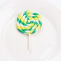 Top view of a large green and yellow swirl clay lollipop on a white ceramic plate - Green Yellow