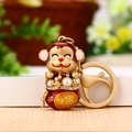 Golden monkey keychain with red enamel, pearls and Fu character on a wooden surface - Matte Golden Lucky Monkey
