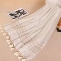 Dettaglio dei ricami in pizzo crema e delle nappe eleganti su una sciarpa in cotone - Beige
