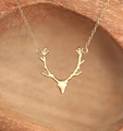 Close-up of golden reindeer antler necklace on a natural wooden texture background - Golden Necklace