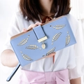 Lichtblauwe lange portemonnee met opengewerkt bladmotief en gouden hanger in hand - Blauw