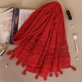 Detail view of red lace scarf with tassel accents and elegant patchwork fabric texture - Red