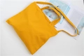 Detail of yellow canvas tote bag with dual handles and crossbody strap on white background - Dark Yellow
