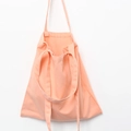 Close-up of minimalist peach canvas tote bag with dual handles and long shoulder straps - Coral Pink
