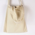 Detalle de bolso tote minimalista de lona crema mostrando las asas dobles y la correa larga - Blanco Roto