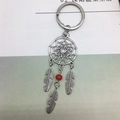 Silver dreamcatcher keychain with feathers and a red bead on a white paper background - Red