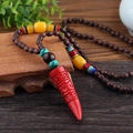 Ethnic style long necklace featuring a red carved horn pendant and brown wood beads - Cinnabar Horn
