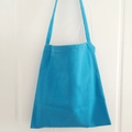 Close-up of bright blue canvas tote bag featuring durable texture and white double stitching - Blue